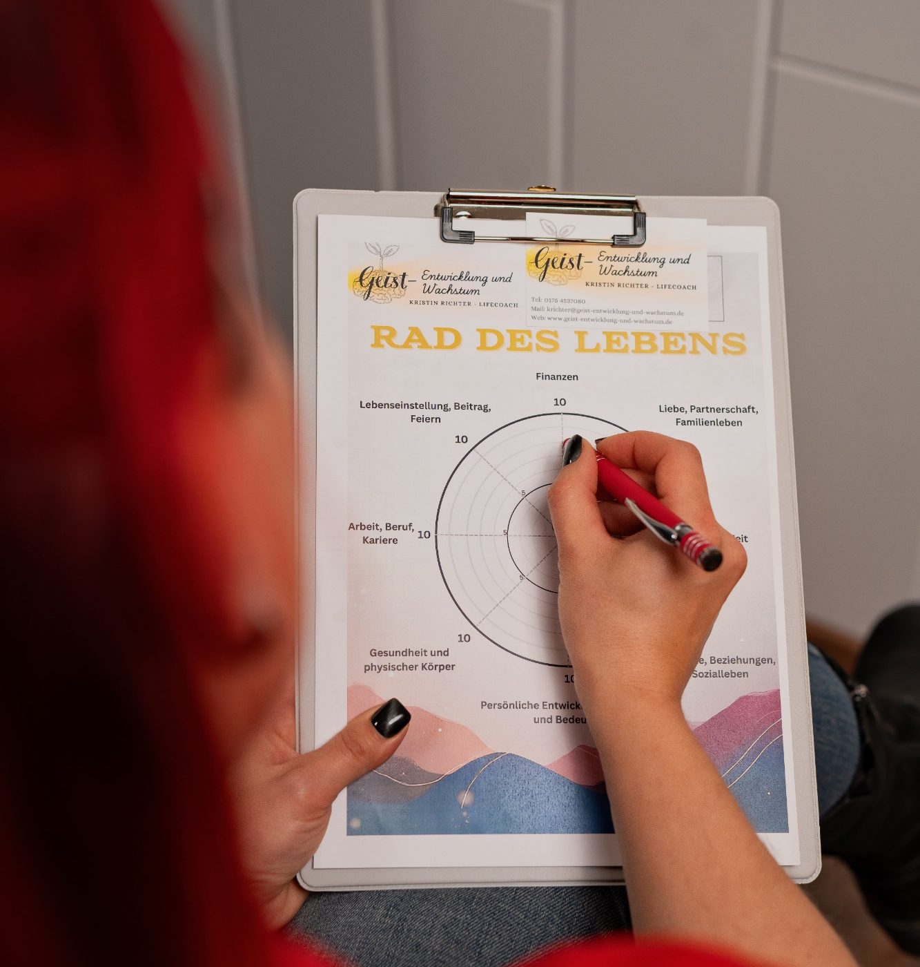 Rad des Lebens Eine Hand mit pinkem Stift schreibt auf ein Arbeitsblatt mit Diagramm und Text.